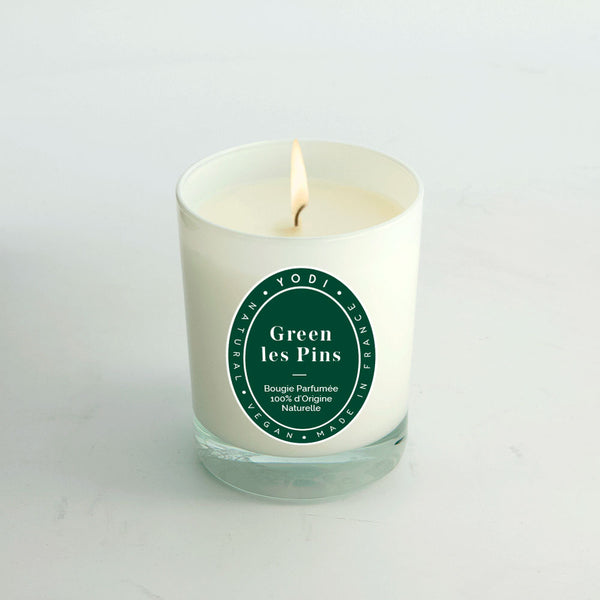 Bougie parfumée Green Les Pins Yodi allumée, verre blanc sur fond clair