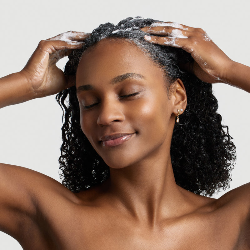 personne en train de s'appliquer et faire mousse shampoing argan